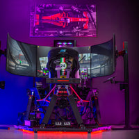 A 6DOF Racing Simulator setup with a Cockpit, Wheelbase, and multiple displays, illuminated by colored lights, positioned on a stage.